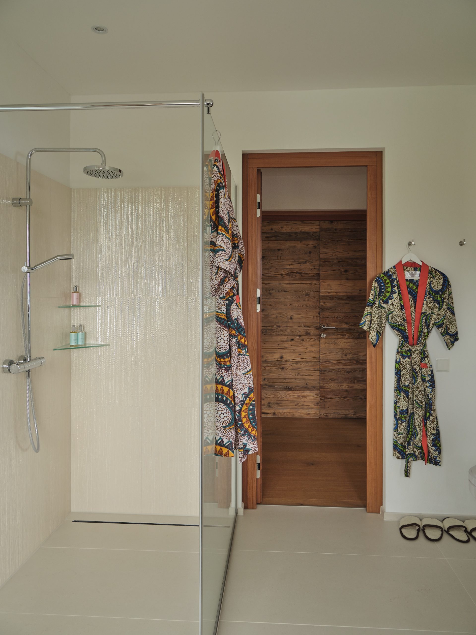 Modern walk-in shower with patterned robes and minimalist wood accents